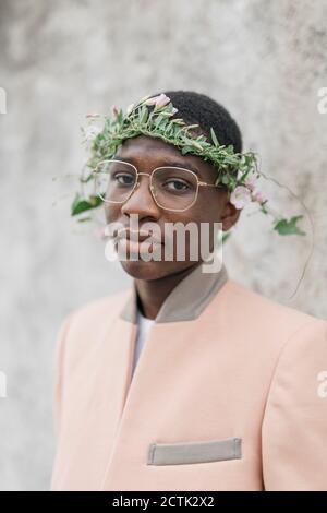 Jeune homme portant des lunettes et du tiara de fleur sur le front Banque D'Images