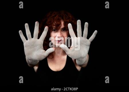 Femme montrant les mains recouvertes de poussière blanche sur fond noir Banque D'Images