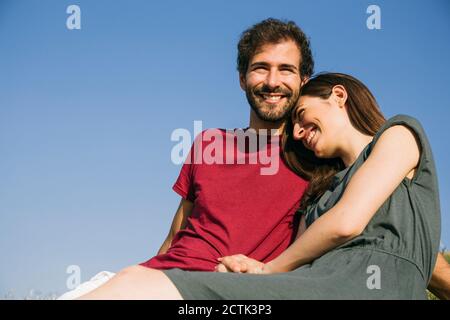 Femme souriant en se penchant sur l'épaule de l'homme contre le ciel clair Banque D'Images