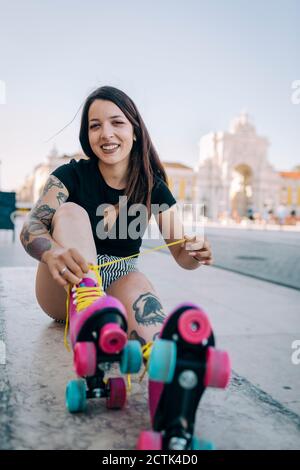 Jeune femme nouant la dentelle de patin à roulettes à Praca do Comercio, Lisbonne, Portugal Banque D'Images