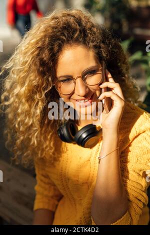 Femme blonde souriante aux cheveux maurires qui parle sur un téléphone portable ville Banque D'Images