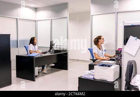 Les pharmaciens féminins utilisent des ordinateurs de bureau à l'hôpital Banque D'Images