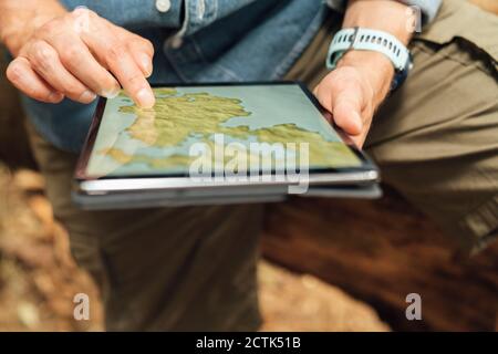 Gros plan des mains de l'homme à l'aide de la carte sur une tablette numérique dans forêt Banque D'Images