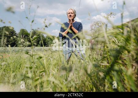 Homme froissé avec les mains jointes sur l'herbe dans le champ agricole Banque D'Images