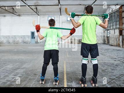 Père et fils en uniforme sportif tenant des bâtons de hockey à cour Banque D'Images