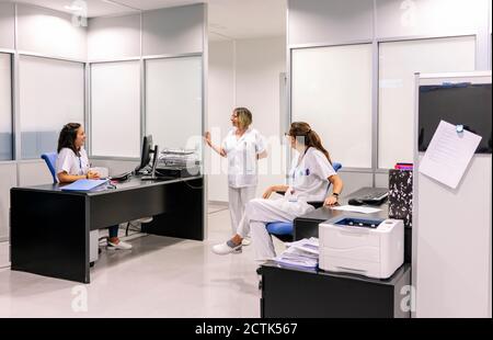 Femme mature parlant avec des collègues assis à un bureau dans la pharmacie Banque D'Images