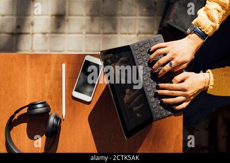 Les mains des étudiantes tapant sur le clavier de la tablette numérique pendant assis au café-terrasse de la ville Banque D'Images