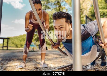 Femme soutenant un homme qui fait des retouches sur un sentier de fitness Banque D'Images