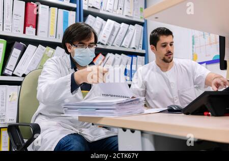 Les médecins masculins font de la paperasserie sur le bureau dans la pharmacie à l'hôpital Banque D'Images