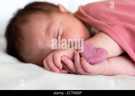 Gros plan de bébé fille nouveau-né en forme de coeur dormant dessus lit à l'hôpital Banque D'Images