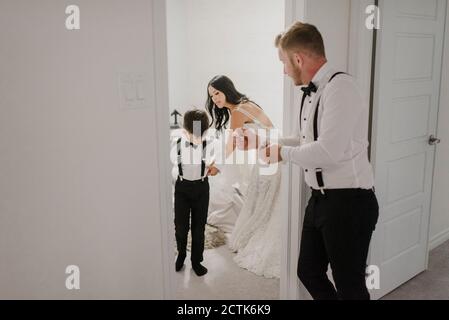 Mère habillant son mariage alors que le père se tient à la porte à la maison Banque D'Images