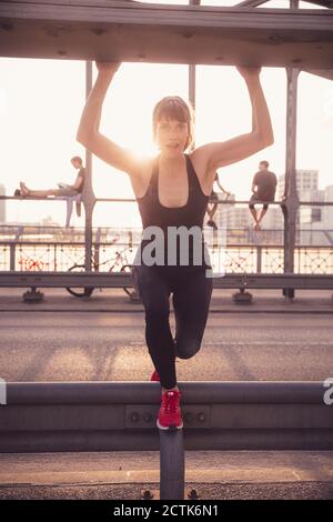Belle femme qui s'étire sur le pont au coucher du soleil Banque D'Images