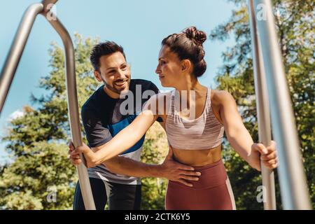 Homme soutenant une femme effectuant des retouches sur un sentier de fitness Banque D'Images