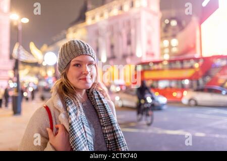 Jeune femme portant des vêtements chauds debout à Piccadilly Circus at nuit Banque D'Images