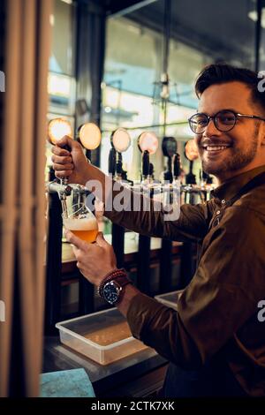 Portrait d'un barkeeper souriant qui puise de la bière dans un pub Banque D'Images