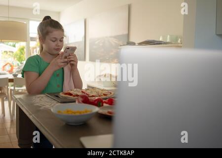 Fille prenant la photo de pizza sur l'île de cuisine Banque D'Images