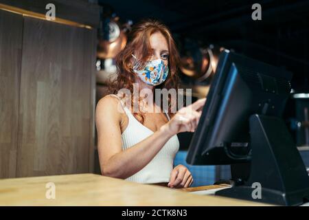 Serveuse prenant commande avec masque de protection sur le visage au restaurant Banque D'Images