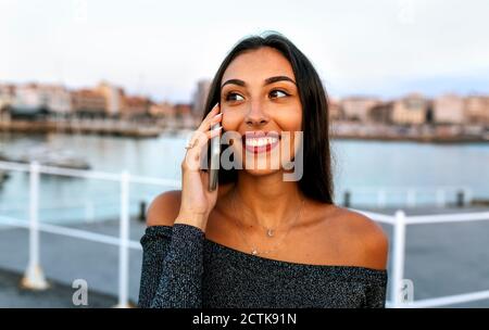 Jeune femme parlant au téléphone en se tenant à la promenade Banque D'Images