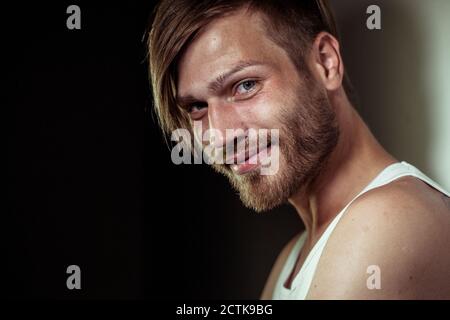 Gros plan sur un beau homme barbu souriant contre le mur Banque D'Images