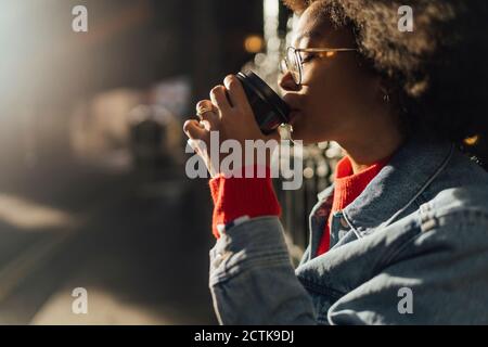 Gros plan de la jeune femme avec les yeux fermés buvant du café pendant debout à l'extérieur Banque D'Images