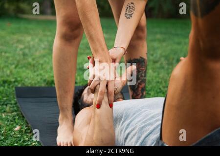 Couple tenant les mains tout en pratiquant acroyoga dans le parc Banque D'Images