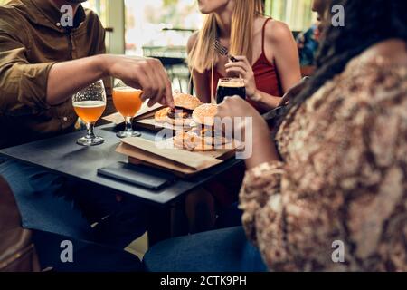 Amis assis à la table dans un pub avec un hamburger et de la bière Banque D'Images