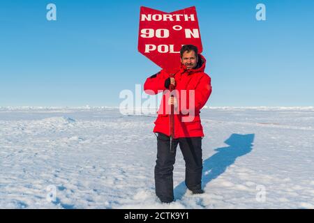 Portrait de l'homme posant avec le panneau sur le pôle Nord Banque D'Images
