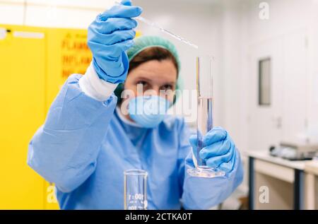 Gros plan de la pharmacienne mélangeant le liquide dans un cylindre gradué à laboratoire Banque D'Images