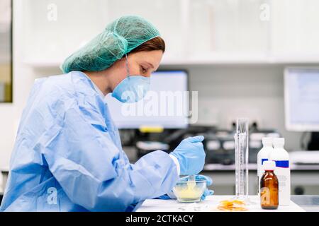 Une pharmacienne prépare un médicament dans du mortier sur une table au laboratoire Banque D'Images