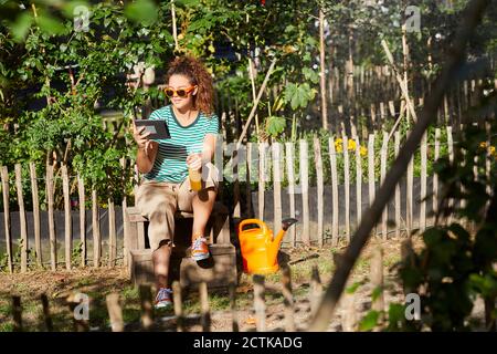 Jeune femme utilisant une tablette dans le jardin Banque D'Images