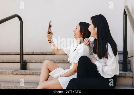 Collègues prenant le selfie tout en étant assis sur l'escalier Banque D'Images