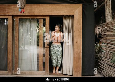 Femme souriante ouvrant la porte de la terrasse Banque D'Images