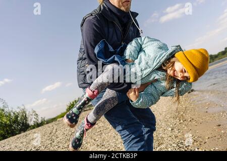 Père transportant sa fille tout en appréciant près de la rive de la rivière Banque D'Images