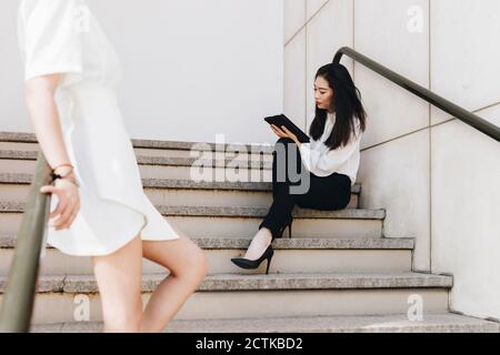 Femme d'affaires debout près d'un collègue dans un escalier Banque D'Images