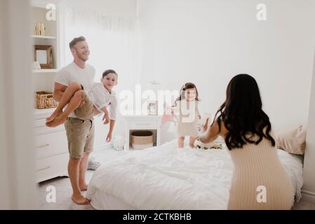 Une famille enjouée au-dessus du lit dans la chambre Banque D'Images