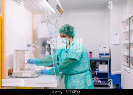 Scientifique féminine mesurant la médecine en poudre à l'échelle en laboratoire Banque D'Images