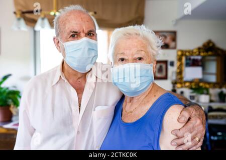 Couple senior portant des masques de protection à la maison Banque D'Images