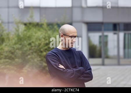 Homme attentionné regardant vers le bas avec les bras croisés sur la piste de marche Banque D'Images