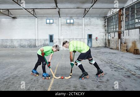 Père et fils face à face lors d'une partie de hockey sur roues sur le terrain Banque D'Images