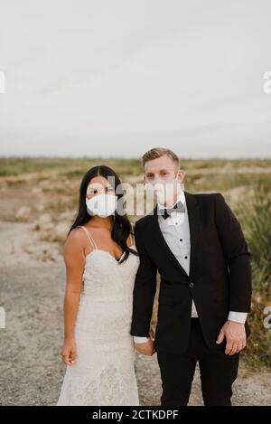 Mariée et marié avec masque de protection dans le champ pendant COVID-19 Banque D'Images