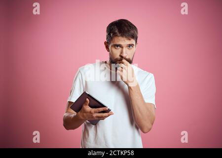 L'homme annonce une tablette sur fond rose codes espace vue rognée des émotions t-shirt blanc modèle nouvelles technologies Banque D'Images