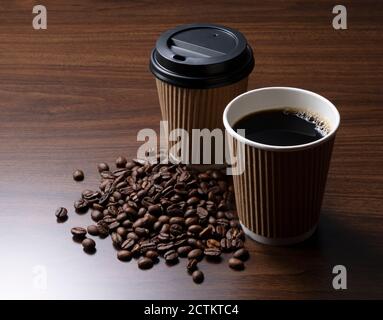 Une tasse de papier de café et de grains de café sur un arrière-plan en bois Banque D'Images