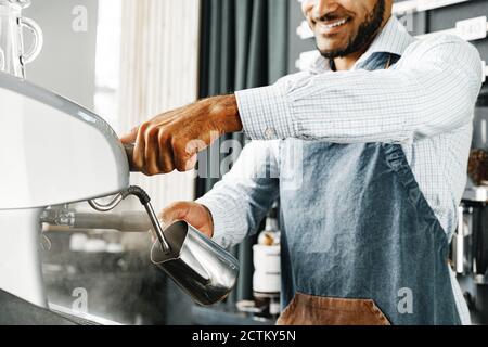 Homme afro-américain Barista préparant du café avec une machine à café professionnelle Banque D'Images