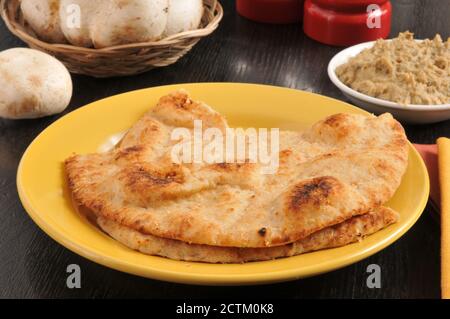 Au four Tandoor pain naan sur une assiette avec un bol de l'hoummos Banque D'Images