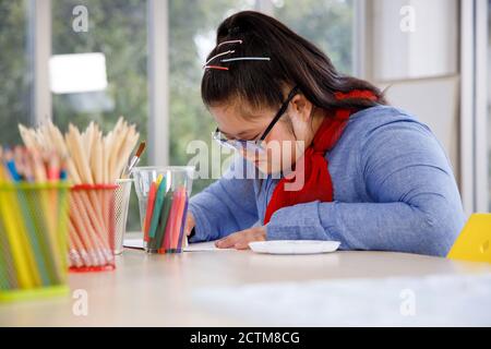 Fille asiatique avec le syndrome de Down dessin image dans la classe d'art. Banque D'Images