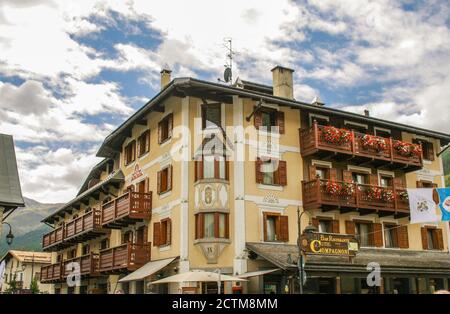 Livigno, province de Sondrio, Valtellina, Lombardie, Italie. Livigno (1816 mètres d'altitude), zone hors taxes, fait partie de la communauté montagneuse d'Alta Valtellina et est une station d'hiver et d'été dans les Alpes. Un bâtiment typique avec des luminaires en bois et des balcons fleuris. Banque D'Images