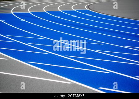 Piste de course courbée bleue et grise avec surface texturée et lignes de séparation blanches. Banque D'Images