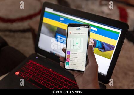 Poole, Royaume-Uni. Jeudi 24 septembre 2020. Un homme installe la nouvelle application NHS Test and Trace sur un smartphone. Le site Web du NHS sur un ordinateur portable derrière. Premier jour du lancement de la nouvelle application de traçage COVID-19. Credit: Thomas Faull/Alamy Live News Banque D'Images