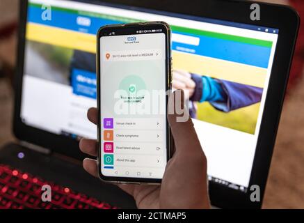 Poole, Royaume-Uni. Jeudi 24 septembre 2020. Un homme installe la nouvelle application NHS Test and Trace sur un smartphone. Le site Web du NHS sur un ordinateur portable derrière. Premier jour du lancement de la nouvelle application de traçage COVID-19. Credit: Thomas Faull/Alamy Live News Banque D'Images