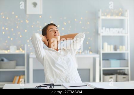 Femme détendue dans son bureau à la maison appréciant beaucoup de sens de réalisation après avoir terminé toutes les tâches quotidiennes Banque D'Images
